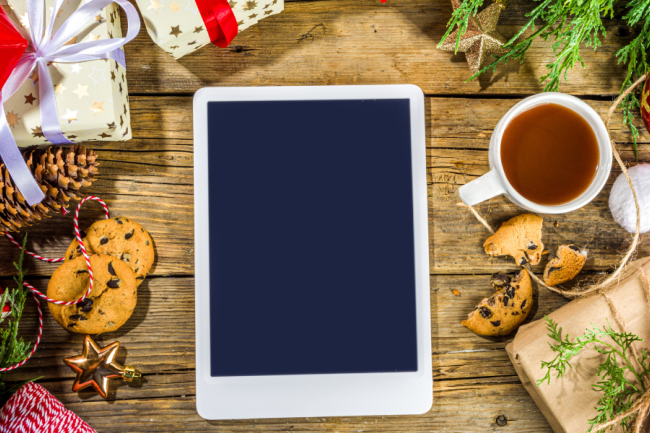 A photo of a tablet surrounded by holiday presents and decorations.